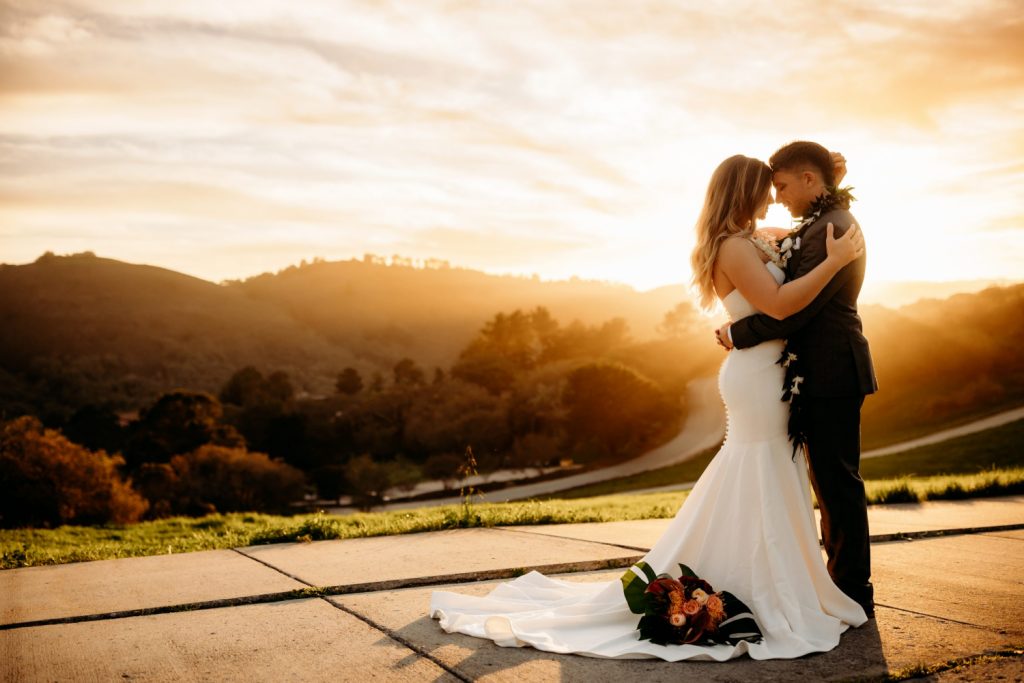 bride and groom hugging close during a beautiful sunset in monterey