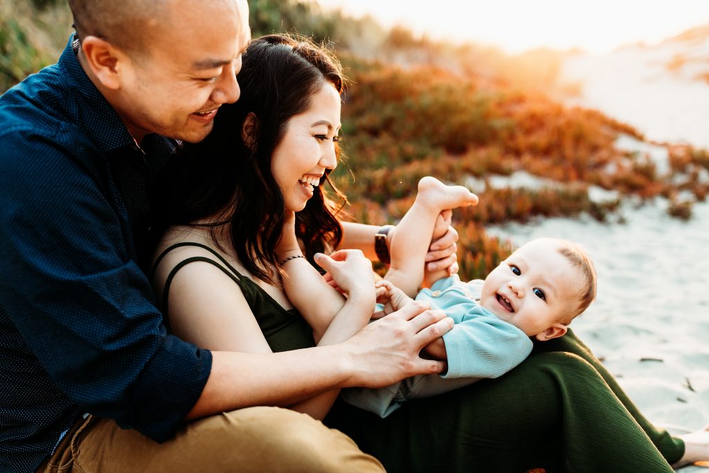 happy baby with mom and dad on the beach at sunset
