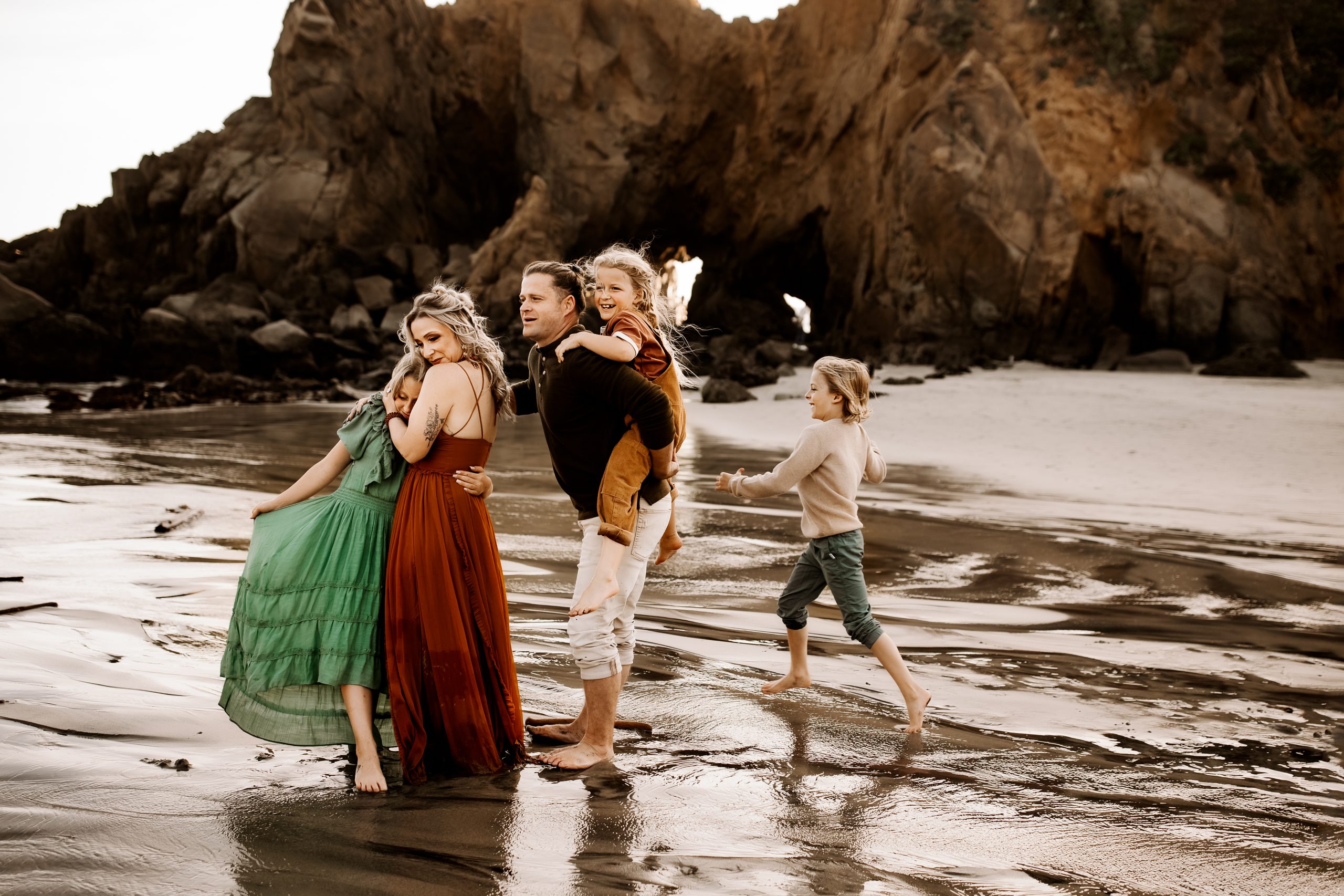 family on the beach hugging and playing near the water in Big Sur